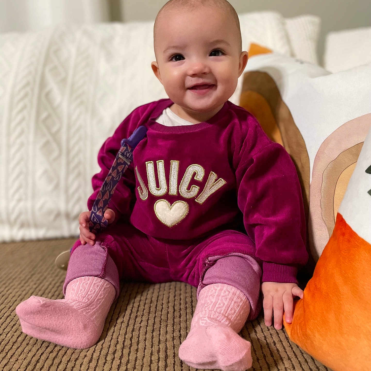 Iris is registered to the contest to win money with this photo: baby, bodypart, clothing, couch, cushion, face, finger, furniture, hand, happy, head, homedecor, hosiery, pants, person, photography, portrait, sitting, smile, sock