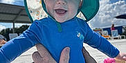 Devon is registered to the contest to win money with this photo: baby, child, blue_hat, swimwear, smiling, outdoor, sunny_day, clouds, sky, hands, tattoo, poolside, water, summer, happy, infant, person, sun_protection, playful, cute