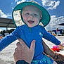 baby, child, blue_hat, swimwear, smiling, outdoor, sunny_day, clouds, sky, hands, tattoo, poolside, water, summer, happy, infant, person, sun_protection, playful, cute