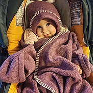 Olivia a rejoint le concours — aidez-le/la à gagner de superbes lots ! baby, blanket, child, clothing, cozy, cute, face, fleece, green, hat, infant, person, portrait, purple, seated, smiling, stroller, warm, wrapped, yellow