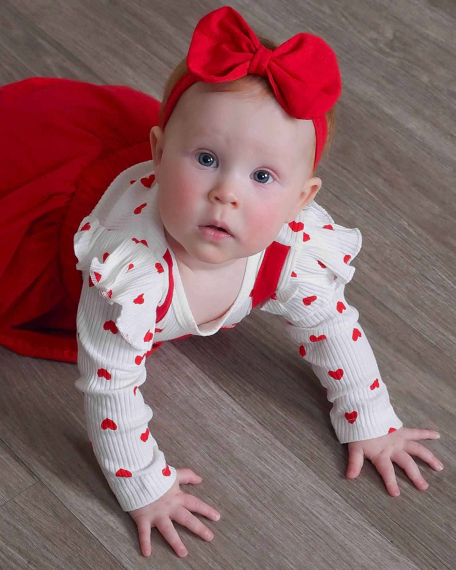 Luna joined the competition — help win amazing prizes! baby, baby_toddler_clothing, carmine, child, collar, costume_hat, dress, face, flooring, foot, happy, head, human_body, kneeling, pattern, person, sitting, sleeve, surprise, textile