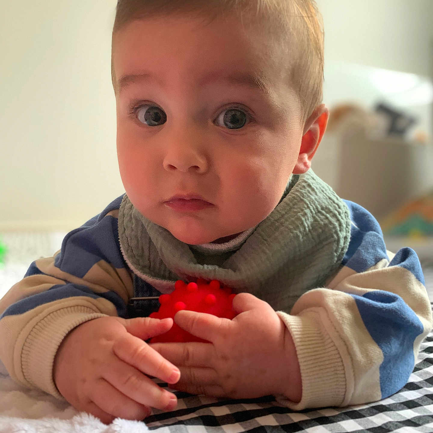 Charlie a rejoint le concours — aidez-le/la à gagner de superbes lots ! baby, bib, blanket, checkered, child, closeup, curious, cute, expression, face, hands, indoors, infant, portrait, red_ball, skin, soft_light, striped_sweater, toy, young