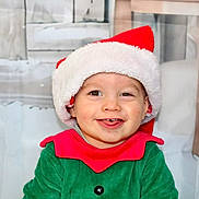 Antoine participe au concours pour gagner de l'argent avec cette photo : child, baby, toddler, santa_hat, christmas, holiday, smile, happy, green_outfit, red_collar, costume, portrait, indoor, background, cheeks, eyes, teeth, cute, festive, winter
