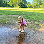Arizona is registered to the contest to win money with this photo: toddler, child, puddle, stick, reflection, mud, grass, outdoor, nature, playing, shoes, pink_clothing, daylight, trees, curious, young_child, dirt, summer, fun, exploration