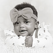Nevaeh is registered to the contest to win money with this photo: adorable, baby, black_and_white, bow, child, close_up, clothing, cute, eyes, face, fluffy_surface, hand, headband, heart_pattern, infant, lying_down, portrait, skin, smile, young