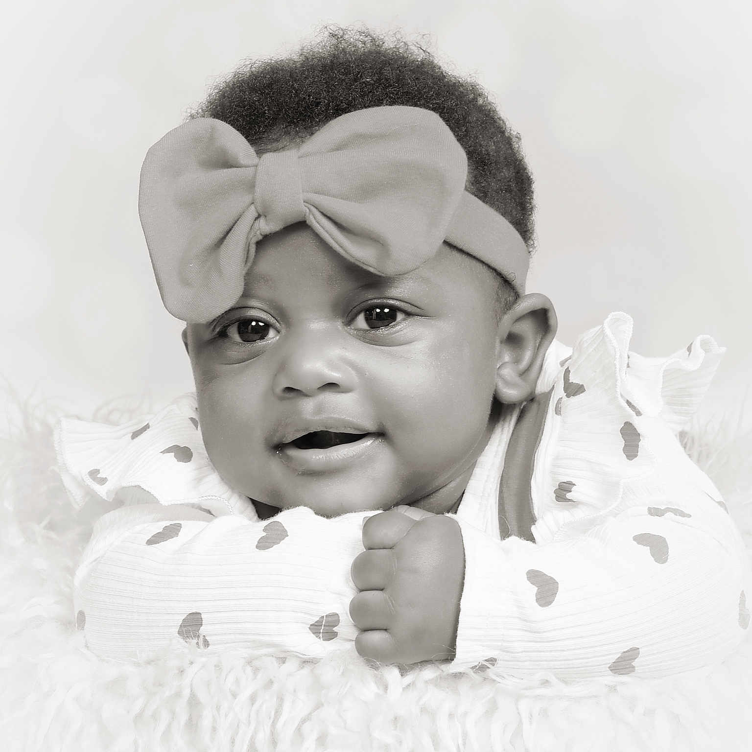 Nevaeh is registered to the contest to win money with this photo: adorable, baby, black_and_white, bow, child, close_up, clothing, cute, eyes, face, fluffy_surface, hand, headband, heart_pattern, infant, lying_down, portrait, skin, smile, young