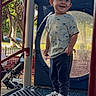 toddler, child, playground, outdoor, smiling, standing, trees, sunlight, play_structure, casual_clothing, sneakers, daylight, recreation, park, happy, person, young_child, fun, nature, background