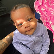 Charm joined the competition — help win amazing prizes! baby, infant, child, onesie, purple_clothing, tattoo, arm, face, eyes, hand, fingers, blanket, pink_blanket, black_fabric, indoor, portrait, sunlight, shadow, cute, cozy