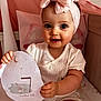 Bonnie joined the competition — help win amazing prizes! baby, infant, child, girl, headband, bow, crib, milestone, sign, pink, socks, cute, smiling, sitting, clothing, portrait, indoor, soft_lighting, happy, young