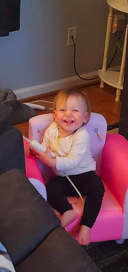 Allie Grace is registered to the contest to win money with this photo: baby, baby_toddler_clothing, chair, cheek, comfort, finger, floor, flooring, furniture, head, human_leg, joy, knee, lap, leg, person, pink, shoulder, smile, sock