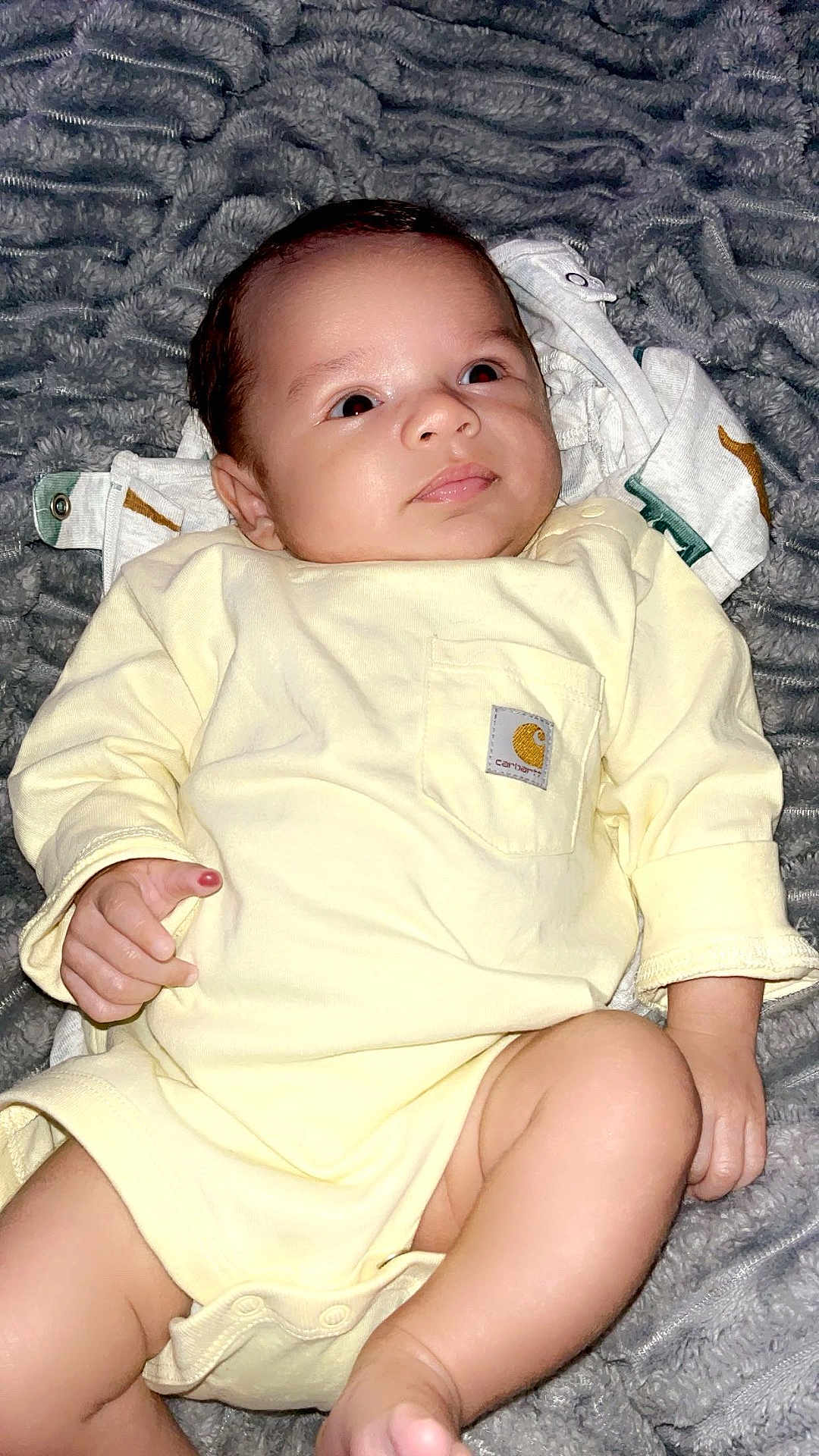 Sebastian joined the competition — help win amazing prizes! baby, infant, onesie, yellow_clothing, blanket, gray_blanket, skin, face, legs, hand, lying_down, indoors, cute, newborn, child, portrait, soft_texture, comfort, clothing_label, expression