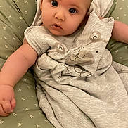 Marcel participe au concours pour gagner de l'argent avec cette photo : baby, infant, cushion, green, gray_clothing, bear_design, face, eyes, arm, hand, soft_fabric, pattern, indoor, comfort, curious, child, person, portrait, closeup, cute