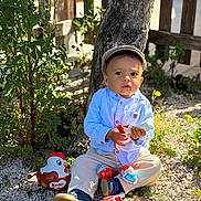 Kevan a rejoint le concours — aidez-le/la à gagner de superbes lots ! beige_pants, blue_shirt, boy, cap, child, cute, daylight, garden, gravel, kinder, nature, outdoor, plants, playful, sitting, sunlight, toddler, toy, tree, young_child