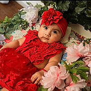 Valeria is registered to the contest to win money with this photo: adorable, baby, colorful, cute, decor, eyes, face, flower_arrangement, hand, headband, indoors, infant, lace, lying_down, pink_flowers, portrait, red_dress, skin, soft_lighting, white_flowers
