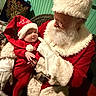 Grayson joined the competition — help win amazing prizes! baby, child, santa_claus, christmas, holiday, red_clothing, hat, beard, gloves, indoor, festive, smile, person, seat, wicker_chair, warm, celebration, costume, toddler, portrait