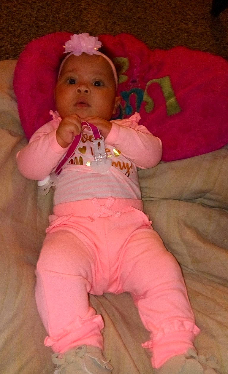 Katalaya is registered to the contest to win money with this photo: abdomen, cheek, child, eye, finger, fun, girl, hair_accessory, hand, headgear, infant, iris, lip, mouth, person, pink, product, sitting, skin, textile