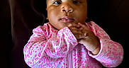 Kehlani joined the competition — help win amazing prizes! adorable, baby, child, closeup, dark_background, face, hands, head, indoor, infant, infant_fashion, looking_at_camera, onesie, patterned_clothing, photography, pink_clothing, portrait, serious_expression, sitting, zipper