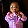 Kehlani joined the competition — help win amazing prizes! baby, infant, child, portrait, sitting, face, hands, onesie, pink_clothing, patterned_clothing, zipper, dark_background, indoor, closeup, looking_at_camera, serious_expression, adorable, photography, infant_fashion, head
