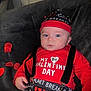 baby, infant, child, valentines_day, red_clothing, hat, suspenders, heart_pattern, couch, rose_petals, portrait, close_up, blue_eyes, indoor, cute, expression, holiday_outfit, lying_down, soft_fabric, photography