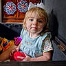 toddler, child, girl, bow, red_ball, indoor, cabinet, wood, crafts, handmade, colorful, face, blue_eyes, clothing, short_sleeves, toy, sitting, portrait, cute, home