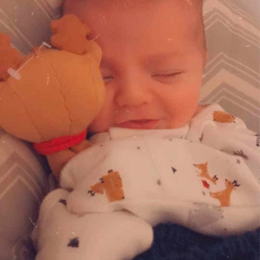 Flynn is registered to the contest to win money with this photo: baby, bed, bedroom, blanket, clothing, cushion, face, furniture, glove, happy, head, homedecor, indoors, newborn, person, photography, portrait, quilt, room, sleeping