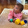 baby, infant, child, pink_clothing, blanket, toy, stacking_cups, floor, wood_floor, indoor, curious, cute, young_child, playing, soft_texture, candid, portrait, toddler, cozy, home