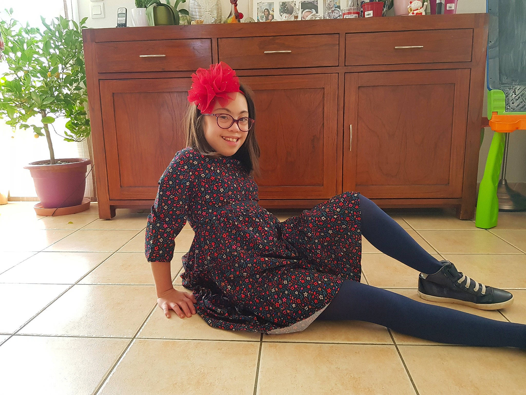 Princess participe au concours pour gagner de l'argent avec cette photo : cabinetry, countertop, face, fashion_design, floor, flooring, flowerpot, hairstyle, headwear, houseplant, joint, joy, knee, person, plant, shoe, shoulder, sleeve, smile, standing