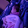 baby, blanket, sleeping, child, purple_light, soft_texture, face, resting, cozy, indoors, cute, peaceful, fabric, pattern, head, wrapped, comfort, portrait, infant, relaxation