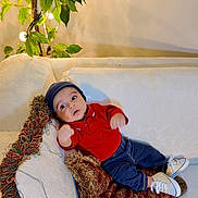 Muhammad joined the competition — help win amazing prizes! baby, child, infant, couch, pillow, plant, indoor, red_shirt, blue_hat, white_shoes, curious, wide_eyes, furniture, decor, cozy, relaxing, home, portrait, casual, seated