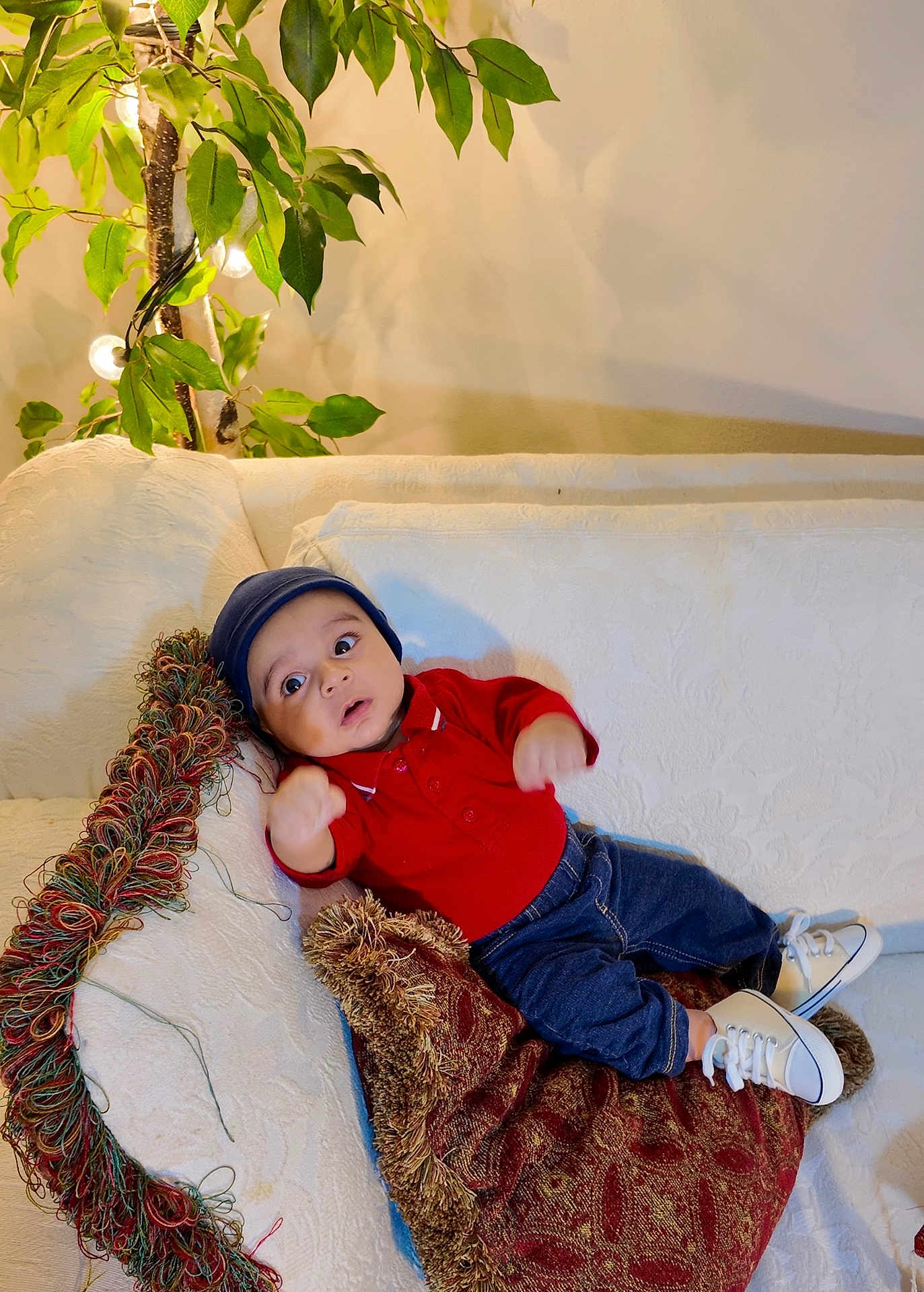 Muhammad joined the competition — help win amazing prizes! baby, child, infant, couch, pillow, plant, indoor, red_shirt, blue_hat, white_shoes, curious, wide_eyes, furniture, decor, cozy, relaxing, home, portrait, casual, seated