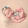 Gabriella is registered to the contest to win money with this photo: newborn, baby, sleeping, infant, portrait, studio_photo, headband, floral, blanket, text_overlay, memories, peaceful, curled_up, raised_feet, bare_arms, soft_lighting, pastel, beige_background, heart, photography