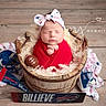 newborn, baby, sleeping, portrait, football, sports_fan, red_clothing, headband, bow, wooden_barrel, rustic, blanket, curly_fur, sports_gear, helmet, sign, wooden_floor, photography, peaceful