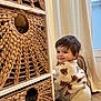 Noa a rejoint le concours — aidez-le/la à gagner de superbes lots ! toddler, child, indoor, woven_basket, shelf, curtain, window, floor, smiling, face, brown_hair, plush_clothing, furniture, home, cozy, natural_light, wood_floor, cute, looking_back, kneeling