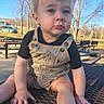 Thomas is registered to the contest to win money with this photo: toddler, child, outdoor, park, overalls, sneakers, bench, metal_table, trees, pavement, sunlight, blue_sky, person, casual_clothing, cute, expression, daytime, young_child, nature, pouting