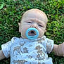 Coda is registered to the contest to win money with this photo: baby, pacifier, grass, outdoor, onesie, infant, child, cute, face, expression, nature, greenery, clothing, lying_down, skin, person, young_child, summer, daylight, portrait