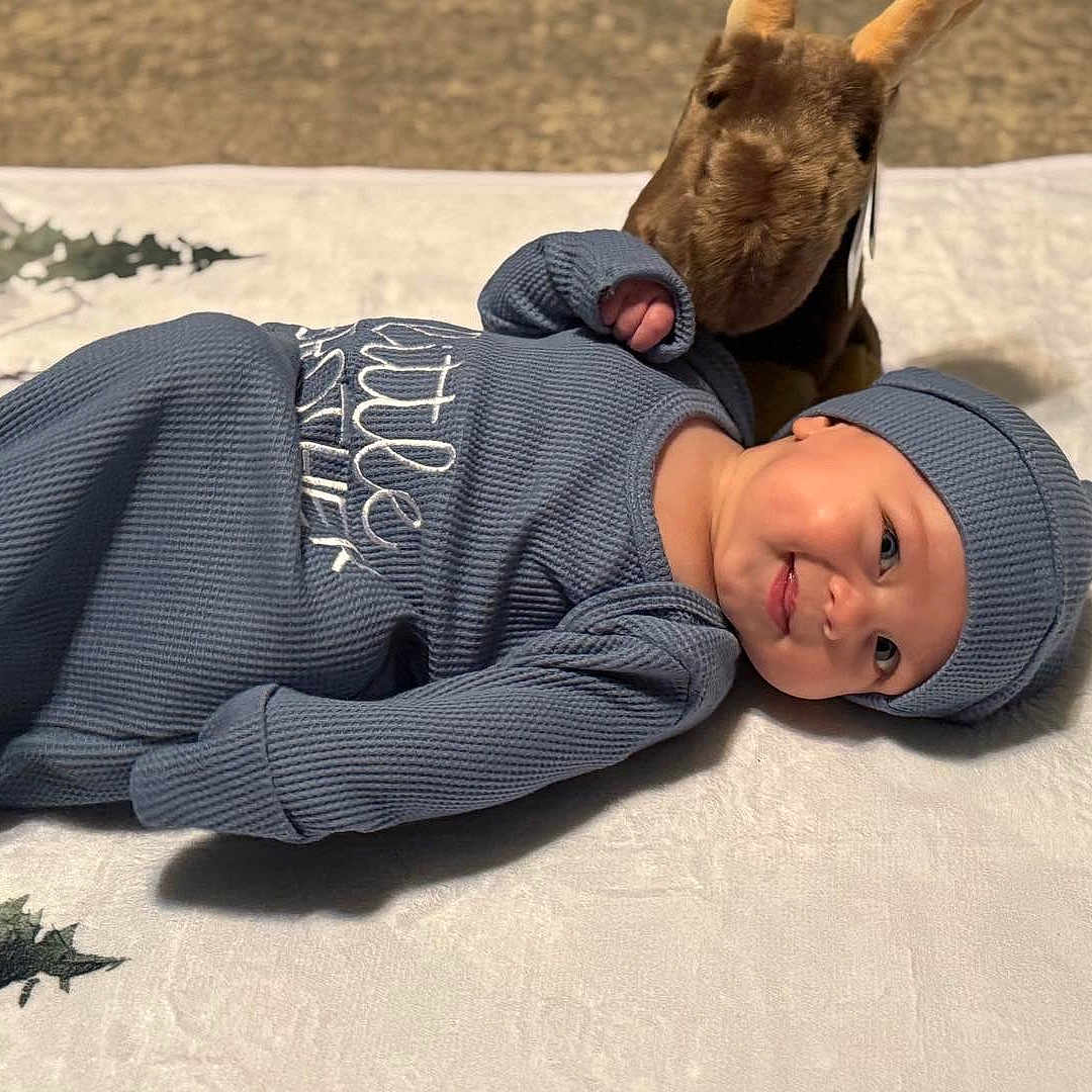 Coda joined the competition — help win amazing prizes! baby, blanket, blue_outfit, child, clothing, cozy, cute, happy, hat, headwear, indoor, infant, kangaroo, lying_down, plush_toy, portrait, resting, smile, soft_texture, young