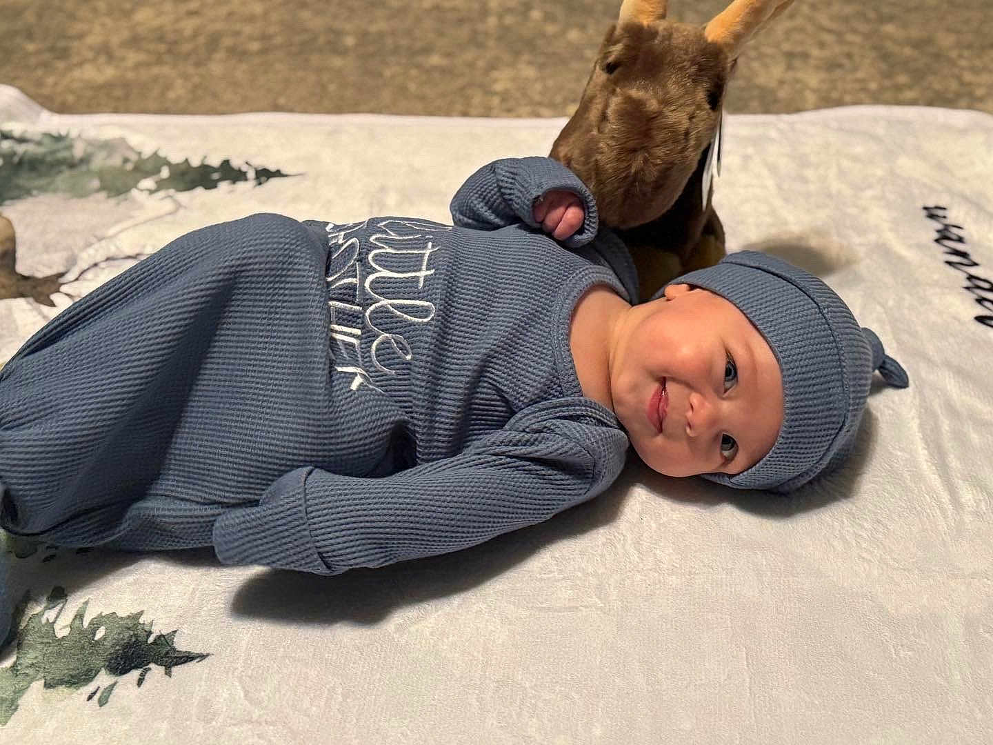 Coda joined the competition — help win amazing prizes! baby, infant, blue_outfit, hat, smile, lying_down, blanket, plush_toy, kangaroo, soft_texture, indoor, cozy, child, cute, portrait, young, happy, clothing, headwear, resting