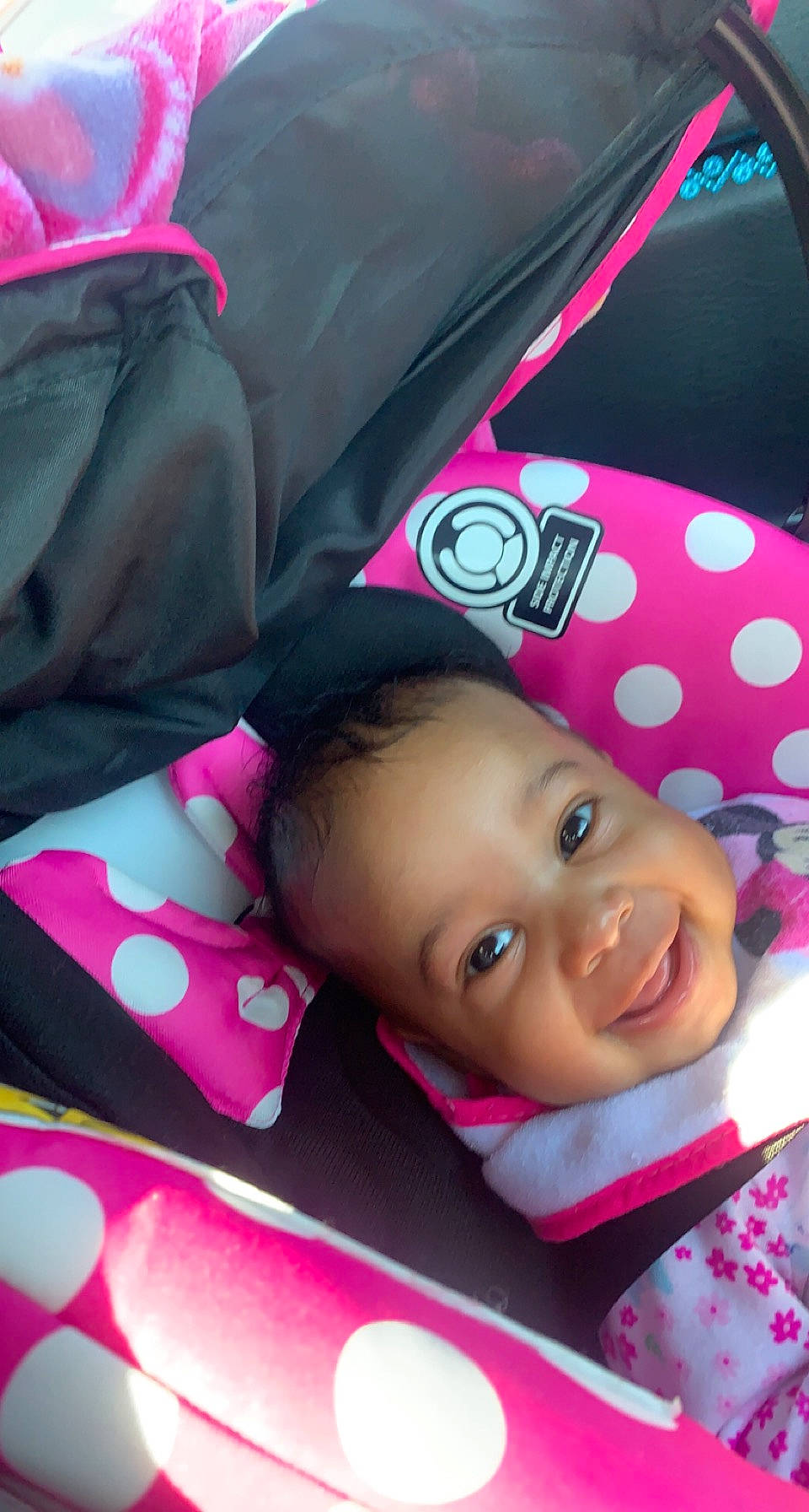 Dasani is registered to the contest to win money with this photo: baby, baby_toddler_clothing, car_seat, carmine, cheek, child, comfort, face, happy, joy, linens, lip, magenta, material_property, pattern, person, pink, red, smile, textile