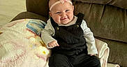 Kinslee joined the competition — help win amazing prizes! baby, infant, smile, headband, bow, overalls, shoes, blanket, couch, furniture, happy, child, indoors, cute, portrait, person, sitting, cozy, soft, home
