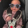 baby, child, sunglasses, car_seat, seatbelt, clothing, infant, cute, person, fashion, accessory, straps, pink_outfit, headwear, safety, portrait, indoor, young_child, eyewear, reflection