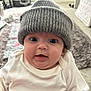 baby, infant, hat, knit_hat, white_clothing, wide_eyes, chubby_cheeks, indoor, carpet, home, cute, portrait, child, person, soft_light, close_up, smiling, wearing, cozy, warm