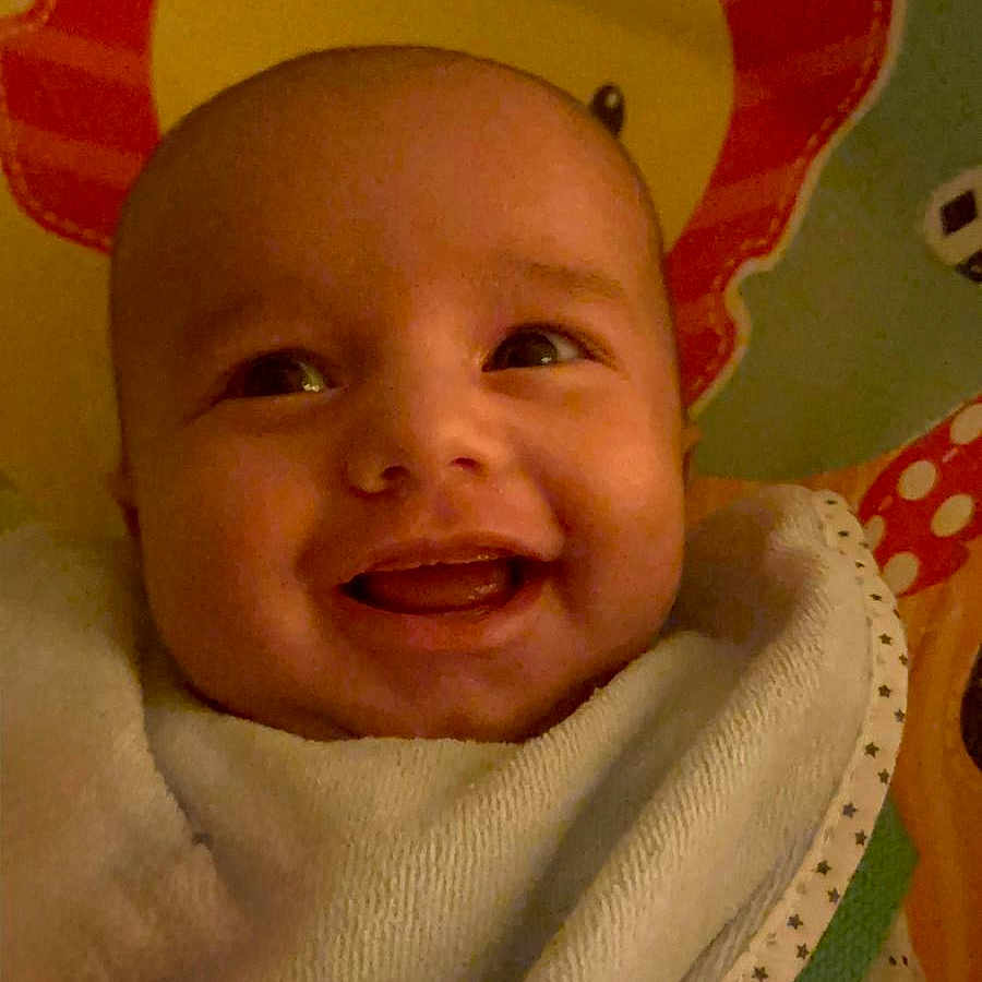 Zayne is registered to the contest to win money with this photo: baby, blanket, child, closeup, colorful, cozy, cute, expression, face, happy, indoor, infant, lion, pattern, pillow, portrait, smile, soft, wrapped, young