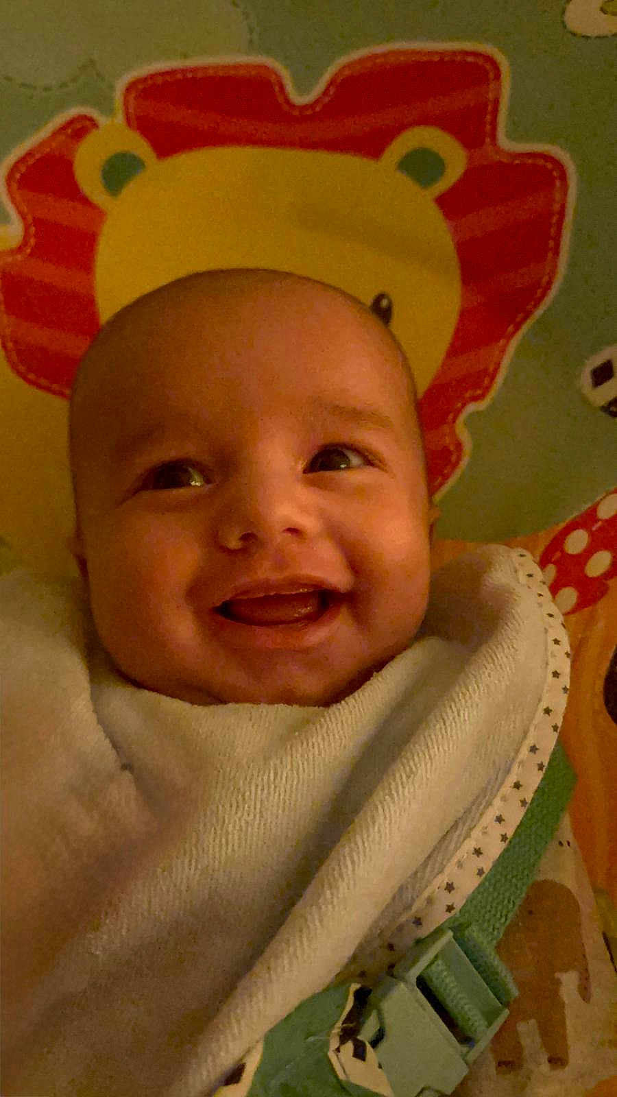 Zayne is registered to the contest to win money with this photo: baby, smile, face, blanket, pillow, lion, child, infant, happy, closeup, indoor, cute, young, cozy, wrapped, colorful, pattern, soft, expression, portrait