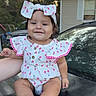 baby, child, infant, smiling, portrait, outdoor, car, vehicle, bow, hair_bow, dress, floral_pattern, cherry_pattern, pink, seated, barefoot, hand, house, trees, daylight