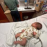 baby, newborn, hospital_room, blanket, bed, person, sink, counter, clothing, medical_supplies, wall, floor, cabinet, toddler, sleeping, indoor, healthcare, caregiver, infant, resting
