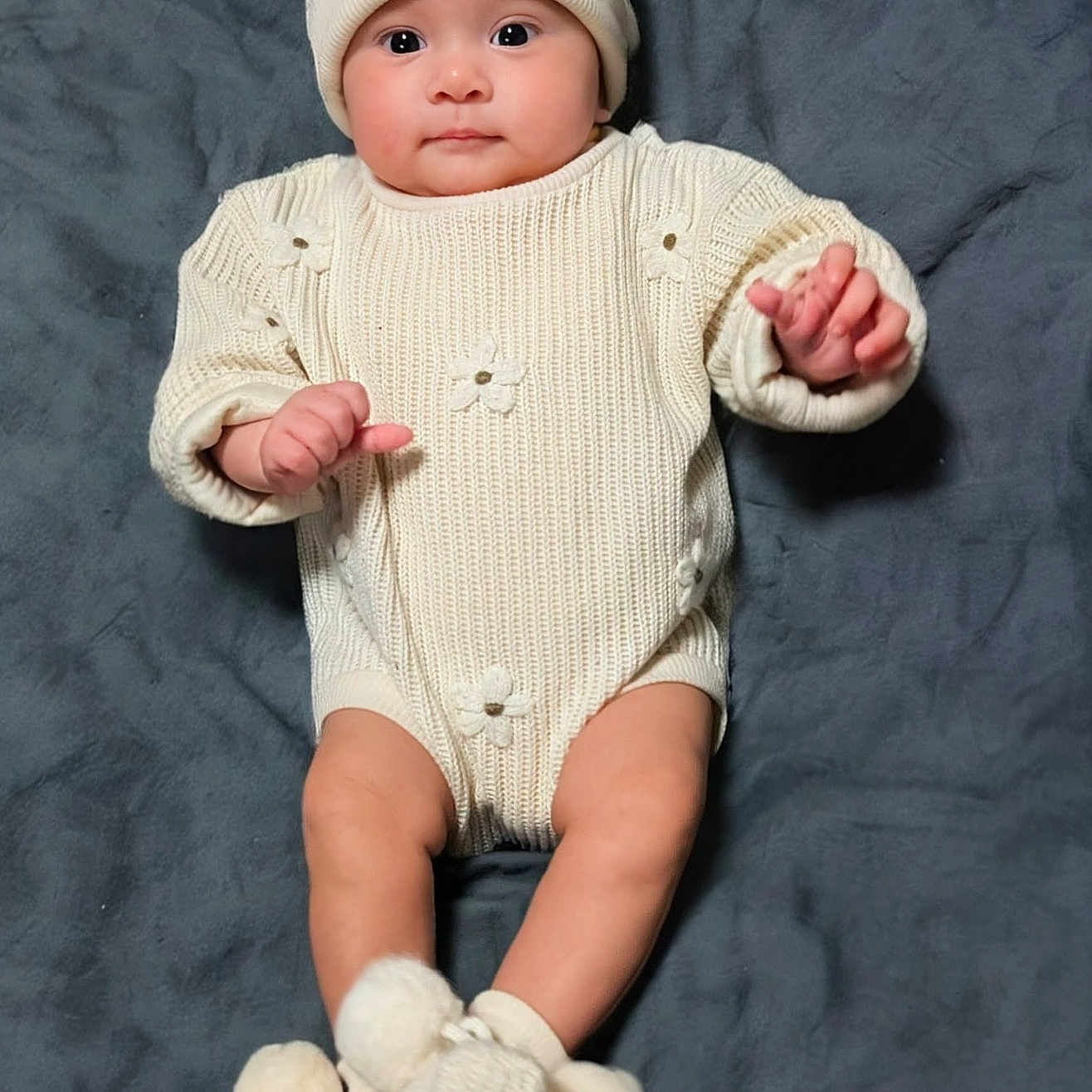 Eleanna is registered to the contest to win money with this photo: baby, blanket, booties, child, clothing, cozy, cute, face, hands, hat, indoors, infant, knitwear, legs, lying_down, pom_poms, portrait, smiling, soft_texture, warm