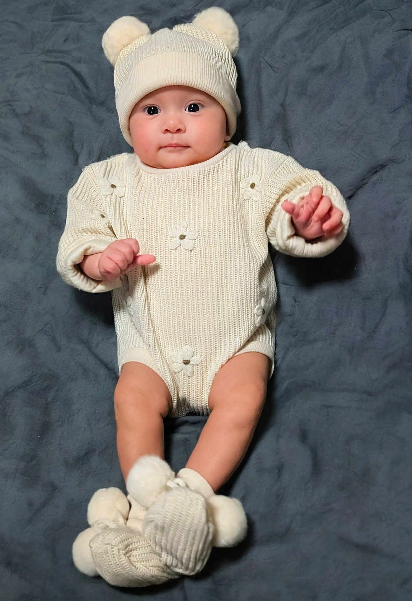 Eleanna is registered to the contest to win money with this photo: baby, blanket, booties, child, clothing, cozy, cute, face, hands, hat, indoors, infant, knitwear, legs, lying_down, pom_poms, portrait, smiling, soft_texture, warm