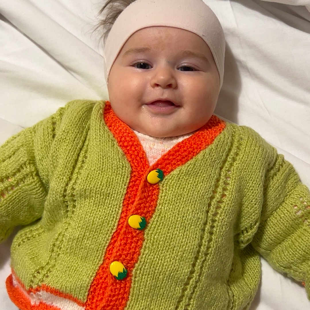 Haissy participe au concours pour gagner de l'argent avec cette photo : baby, child, chubby_cheeks, cozy, cute, green, happy, headband, indoors, infant, knitted_cardigan, lying_down, orange, portrait, smiling, soft_lighting, toddler, warm_clothing, white_bed, yellow_buttons