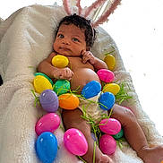 Island is registered to the contest to win money with this photo: baby, infant, bunny_ears, easter_eggs, colorful, plastic_eggs, blanket, cute, holiday, spring, decorative_grass, indoors, soft_texture, newborn, lying_down, skin, foot, hand, curious, portrait