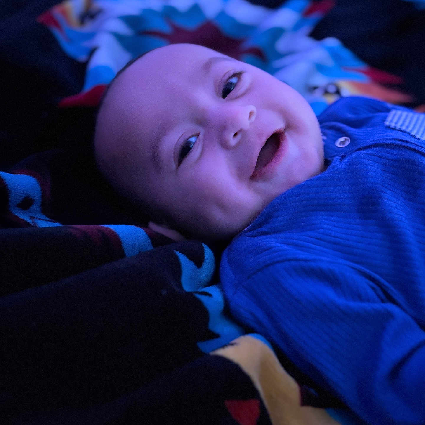 Toa-Malosi is registered to the contest to win money with this photo: baby, blanket, blue_clothing, child, closeup, cozy, cute, dimples, face, happy, indoor, infant, lying_down, patterned_blanket, person, portrait, sleepwear, smiling, soft_lighting, warmth